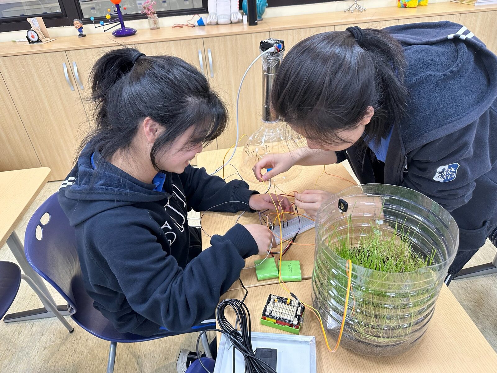 Students wiring IoT sensors and microcontrollers for automated biodome project